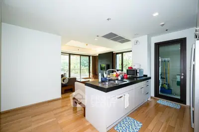 Modern open-layout kitchen with sleek design and spacious living area, featuring large windows and natural light.