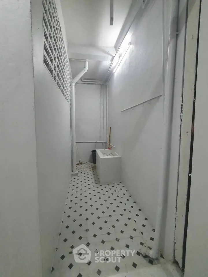 Narrow utility room with tiled floor and basic sink, ideal for laundry or storage.