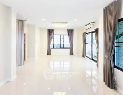 Spacious and bright living room with large windows and elegant curtains
