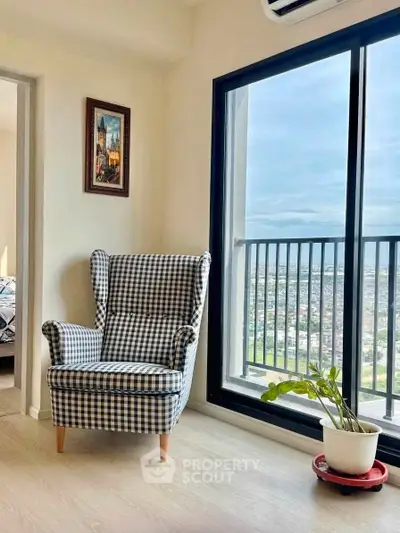 Charming corner with checkered armchair and city view from high-rise apartment balcony.