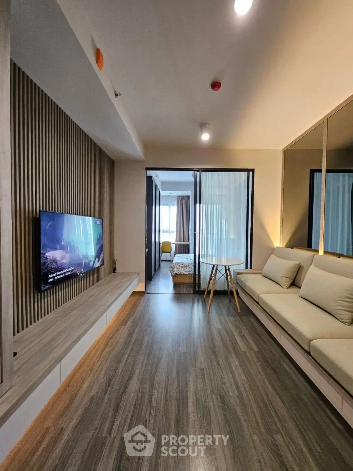 Modern living room with sleek design and cozy seating area, featuring a view into a stylish bedroom.