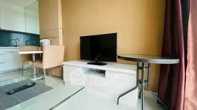 Modern living room with sleek TV setup and dining area in stylish apartment.
