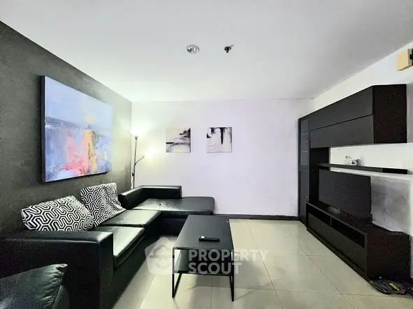 Modern living room with sleek black furniture and contemporary art on white walls.