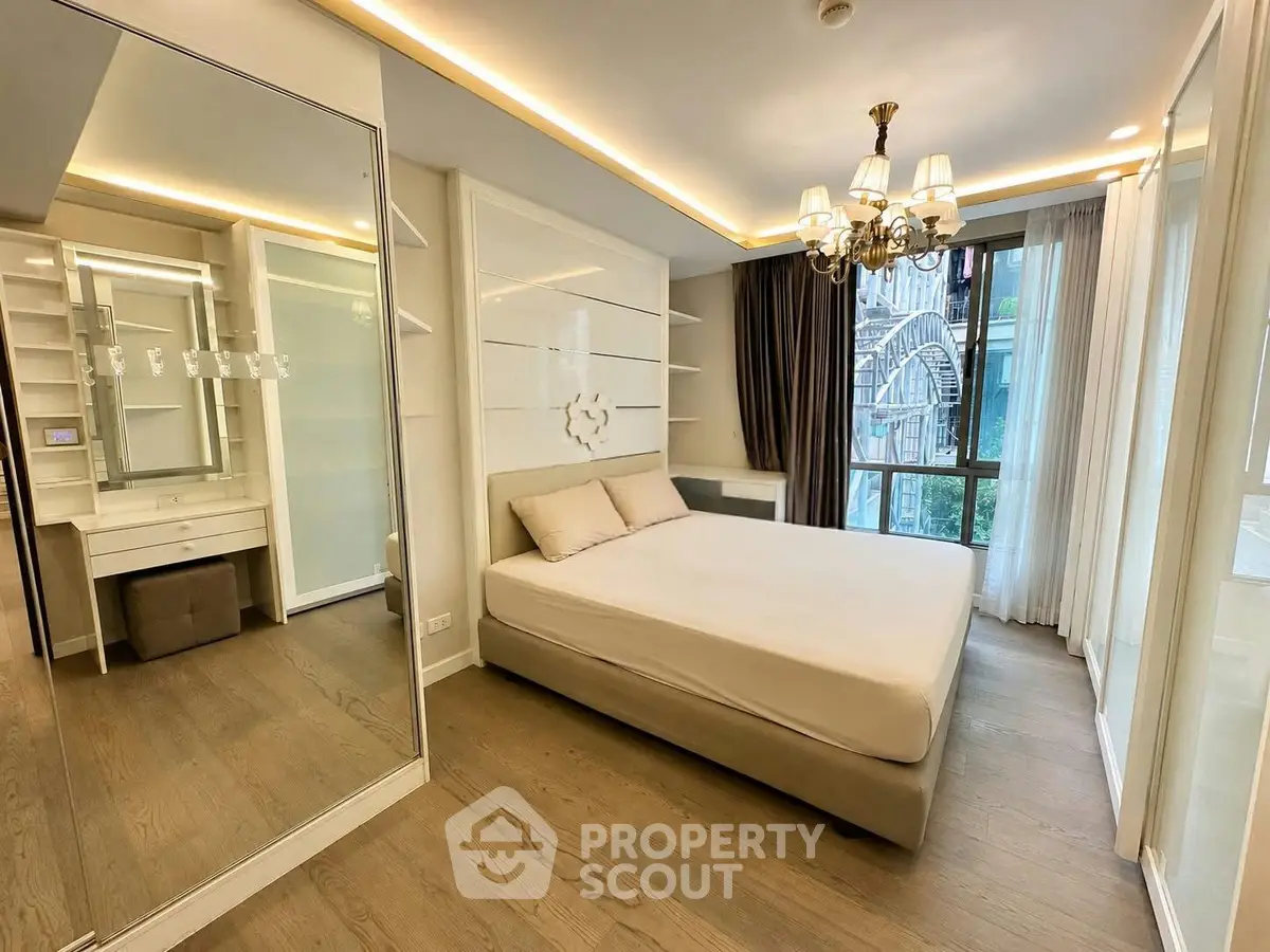 Luxurious bedroom with elegant chandelier and large window offering stunning city view
