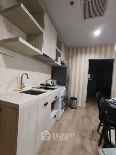 Modern kitchen with sleek appliances and open shelving in a cozy apartment setting.