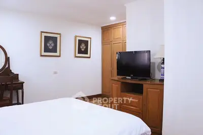 Cozy bedroom with wooden furniture and modern TV setup, perfect for relaxation.