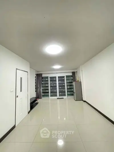 Spacious unfurnished living room with large windows and tiled flooring, perfect for customization.