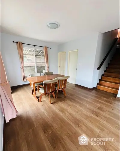 Spacious dining area with wooden flooring and elegant staircase in a modern home interior.