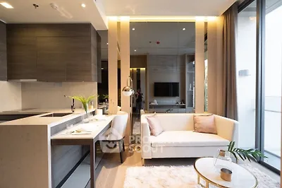Modern open-layout living room with stylish kitchen and cozy seating area, featuring elegant decor and natural light.