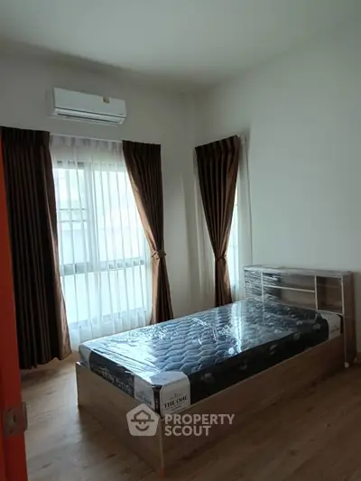 Cozy bedroom with natural light, featuring a bed and air conditioning, ideal for restful living.