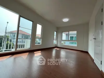 Spacious empty room with large windows and wooden flooring, ideal for customization.