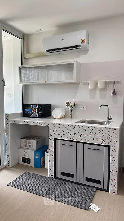 Modern kitchen with terrazzo countertops, air conditioning, and sleek cabinetry in a bright, airy space.