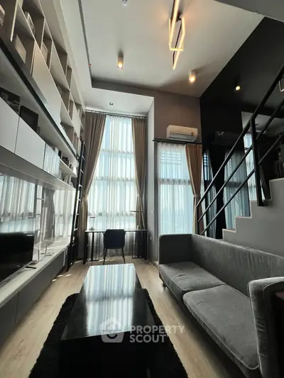 Modern living room with high ceilings, sleek furniture, and large windows for natural light.