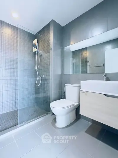 Modern bathroom with sleek design, featuring a glass shower and contemporary fixtures.