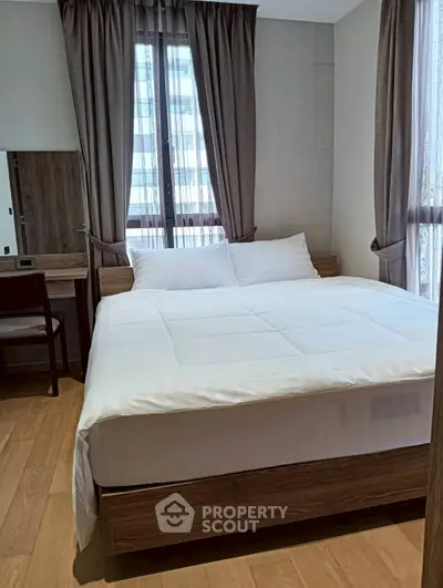 Cozy bedroom with large window and modern furnishings, perfect for relaxation.