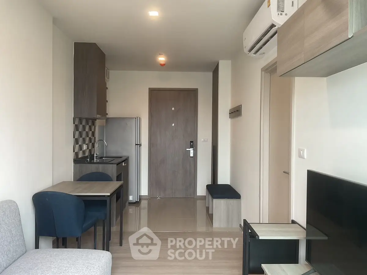 Modern studio apartment with compact kitchen and cozy living area, featuring sleek furniture and contemporary design.