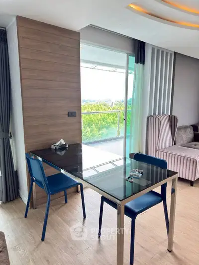 Modern living room with glass table and chairs, featuring a large balcony with scenic view.