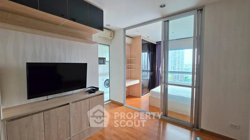 Modern apartment interior with living room and bedroom, featuring wooden flooring and large windows with city view.