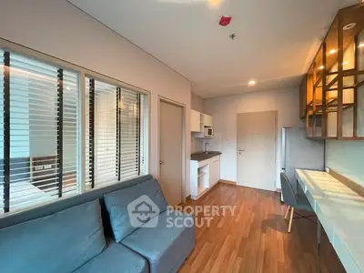 Modern living room with sleek kitchen in open layout, featuring wooden floors and stylish furniture.