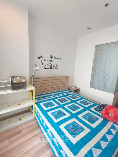 Cozy bedroom with vibrant blue quilt and modern decor, perfect for a restful night's sleep.