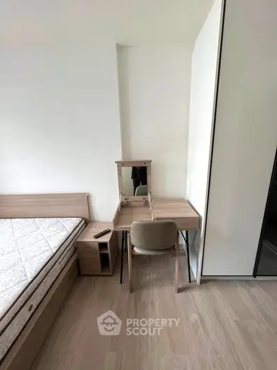 Modern bedroom with minimalist furniture and wooden flooring, featuring a bed and a stylish vanity desk.