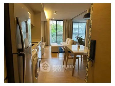 Modern open-plan living room with kitchen, featuring stylish decor and large windows with a view.