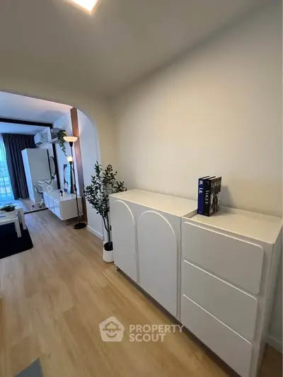 Modern living room with sleek white furniture and wooden flooring, featuring a cozy ambiance.