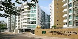 Modern apartment building exterior with Harmony Living sign, showcasing contemporary architecture.