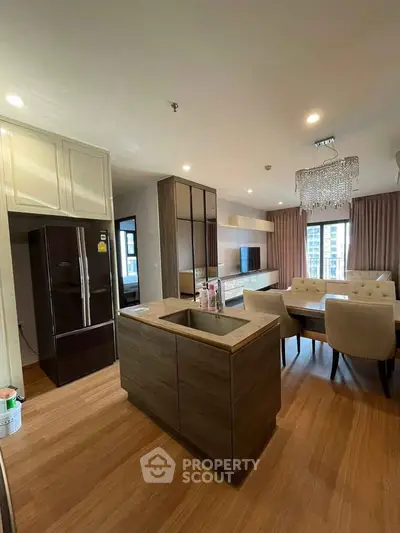 Modern open-layout kitchen and living room with elegant chandelier and stylish furnishings.