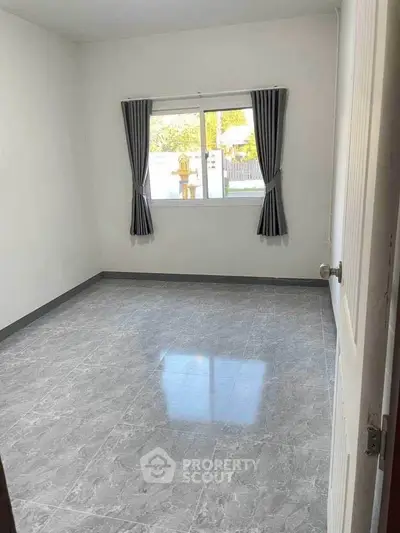 Spacious empty room with tiled floor and window view, perfect for customization.