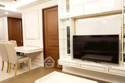 Elegant living room with modern TV setup and dining area, featuring stylish wooden doors and chic decor.