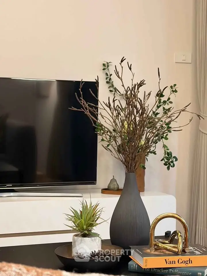 Stylish living room with modern decor, TV, and elegant plant arrangement.