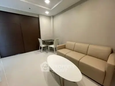 Modern living room with beige sofa and sleek dining area in minimalist apartment.