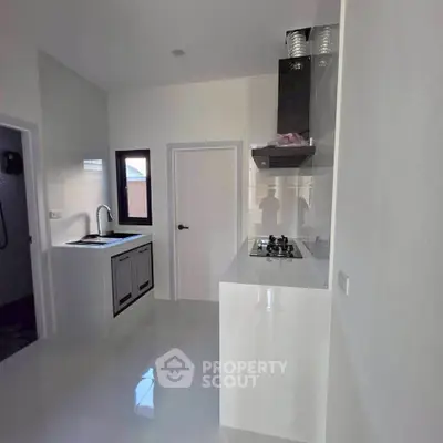 Modern kitchen with sleek white cabinetry and gas stove in a contemporary home.