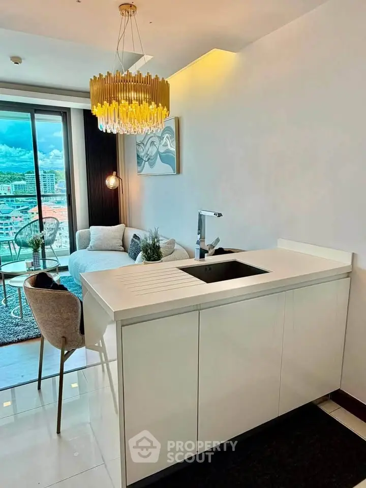 Modern open-plan living room with chic decor and city view, featuring elegant lighting and sleek kitchen island.