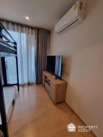 Modern bedroom with bunk bed, TV, and air conditioning in a cozy apartment.