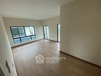 Spacious empty room with large windows and wooden flooring, perfect for customization.