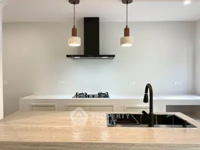 Modern kitchen with sleek countertops, gas stove, and stylish pendant lighting.