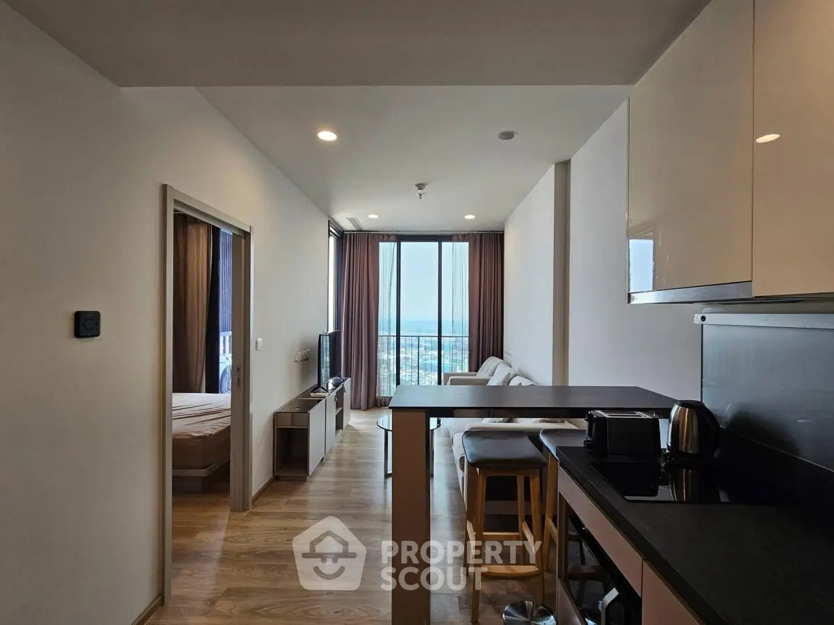 Modern open-layout apartment with sleek kitchen and stunning city view from living room.