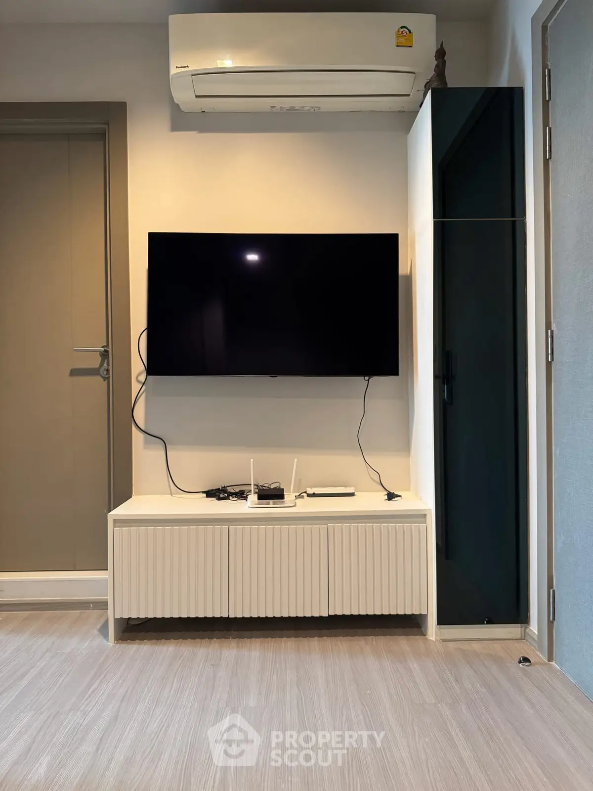 Modern living room with sleek TV setup and air conditioning, perfect for comfortable living.