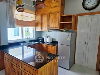Charming kitchen with wooden cabinets and modern appliances, featuring a sleek black countertop and natural light.