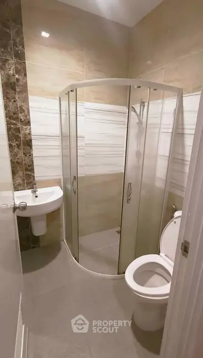 Compact modern bathroom with corner shower and sleek fixtures