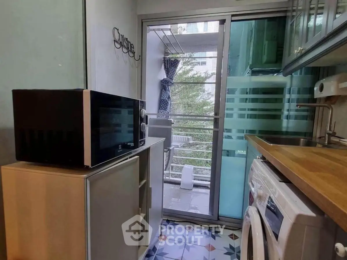 Compact kitchen with modern appliances and balcony view
