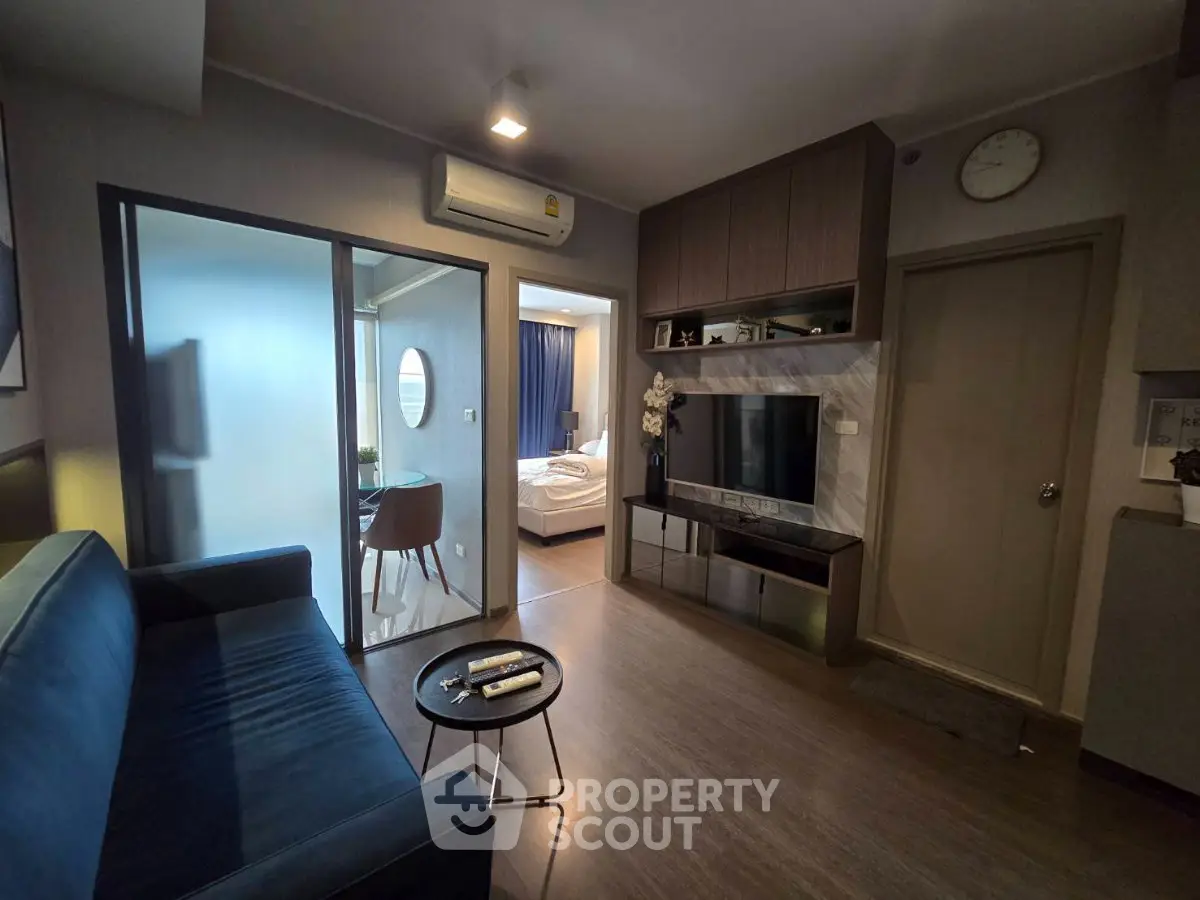 Modern living room with sleek design and view into cozy bedroom