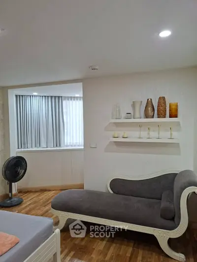 Elegant living room with stylish chaise lounge and decorative vases on display shelves.