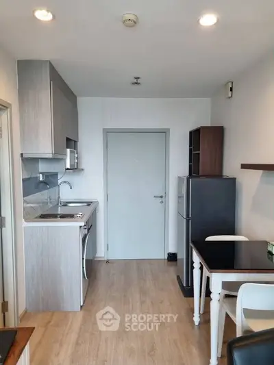 Modern kitchen with sleek cabinetry, compact dining area, and contemporary appliances in a stylish apartment.