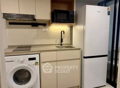 Modern compact kitchen with washing machine and fridge in a stylish apartment.