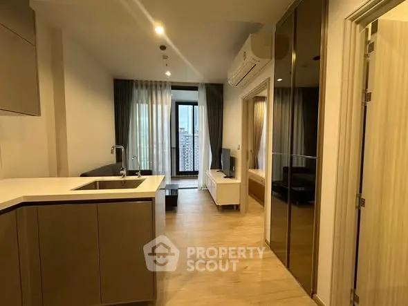 Modern apartment interior with open kitchen and living area, featuring sleek design and large windows.