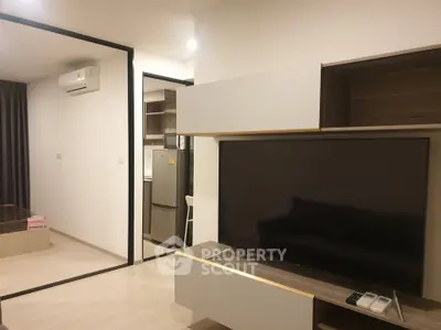 Modern apartment interior with sleek living room and kitchen area, featuring a large TV and air conditioning.