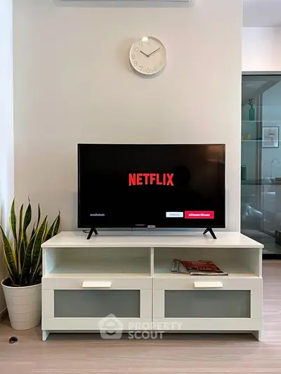 Modern living room with sleek TV stand and Netflix on screen, stylish decor and plant accent.